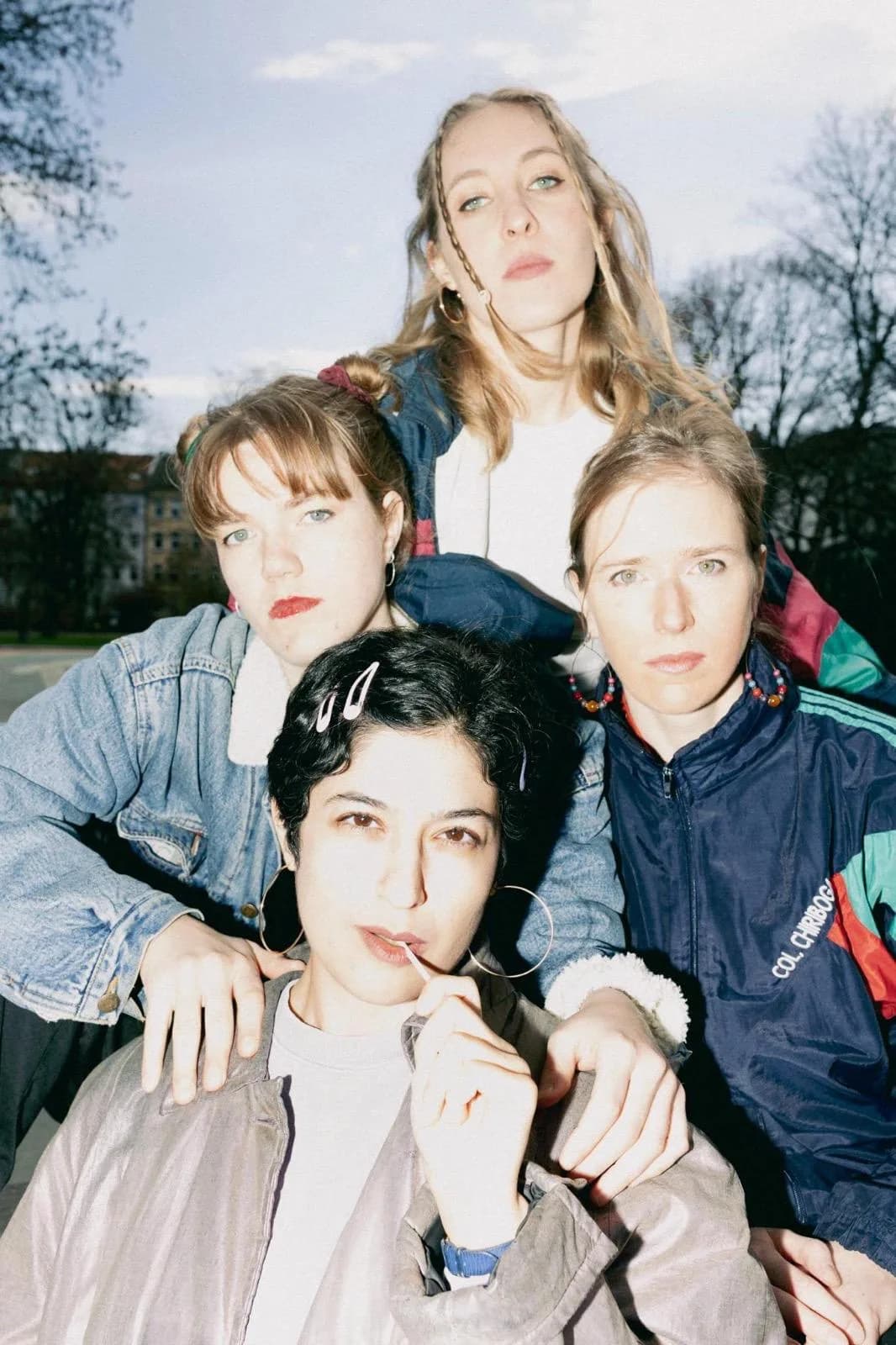 Vier Performerinnen aus dem Faust.Margarete-Ensemble in 90er-Streetwear, Gruppenporträt im Park.